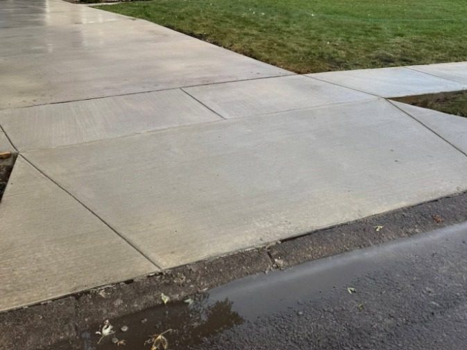 Finished concrete driveway meeting the street at a new apron, jointed on a grid