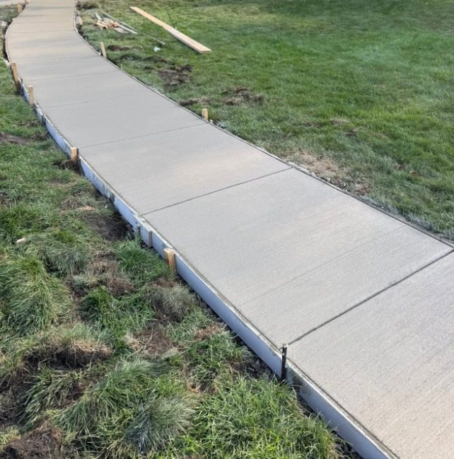 Curved concrete walkway through a lawn, broom finished and still in its forms